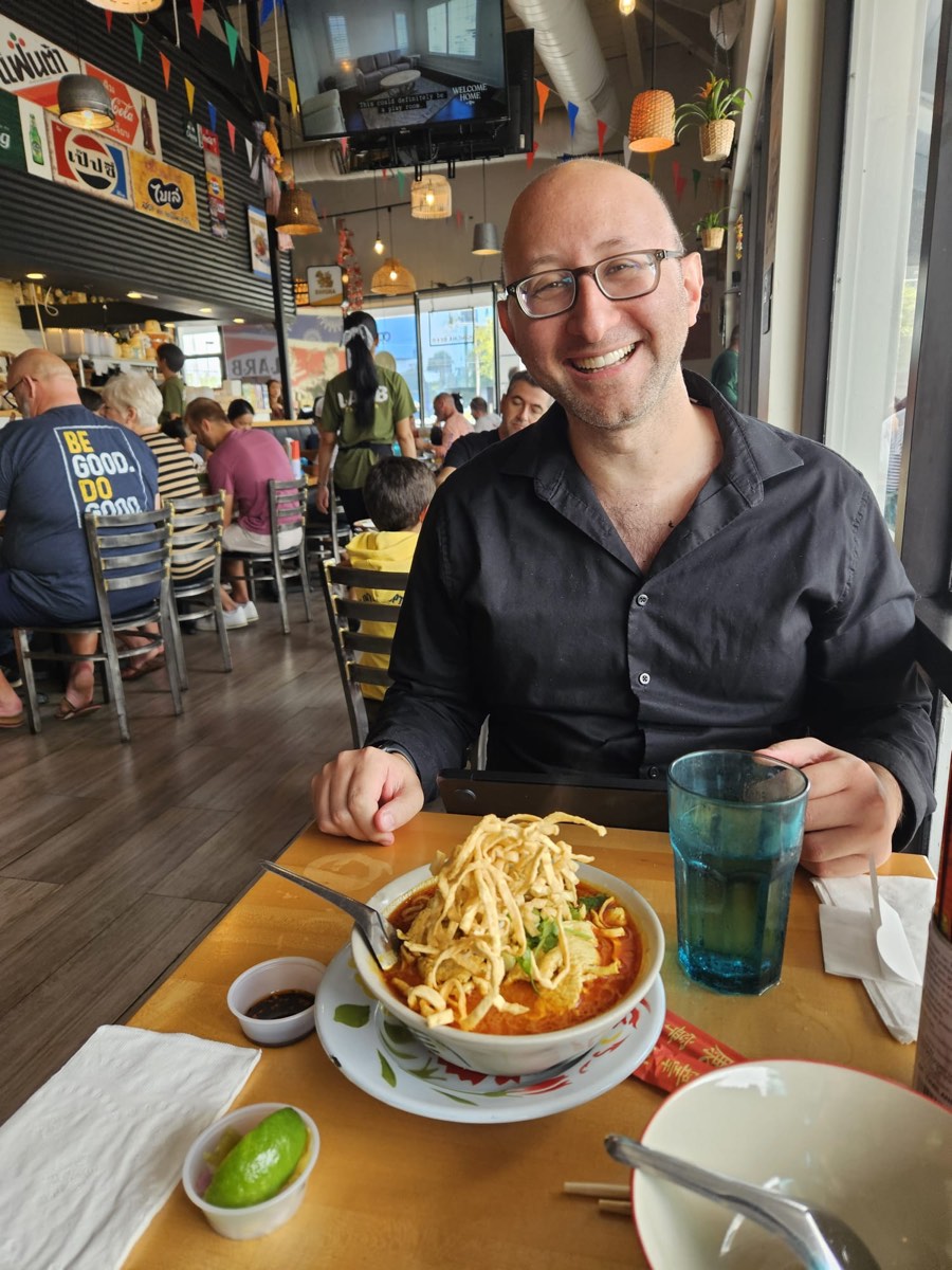 FIG. 01 · April 6, 2025 David grinning at a Thai restaurant table behind a bowl of khao soi, April 6, 2025