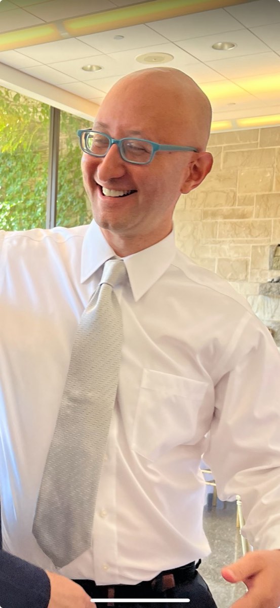 FIG. 02 · August 19, 2024 David laughing mid-conversation in a white shirt and silver tie, August 19, 2024