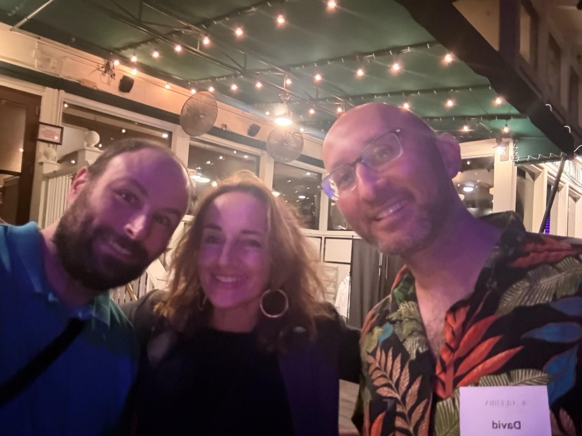 FIG. 04 · September 3, 2026 David in a leaf-print shirt, smiling in a selfie beside two other guests under string lights on a patio at night, September 3, 2026